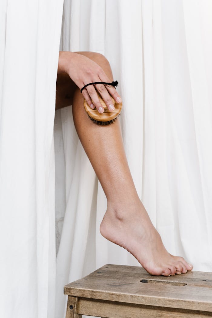 Close-up of leg exfoliation using a bamboo dry brush, promoting eco-friendly skincare.